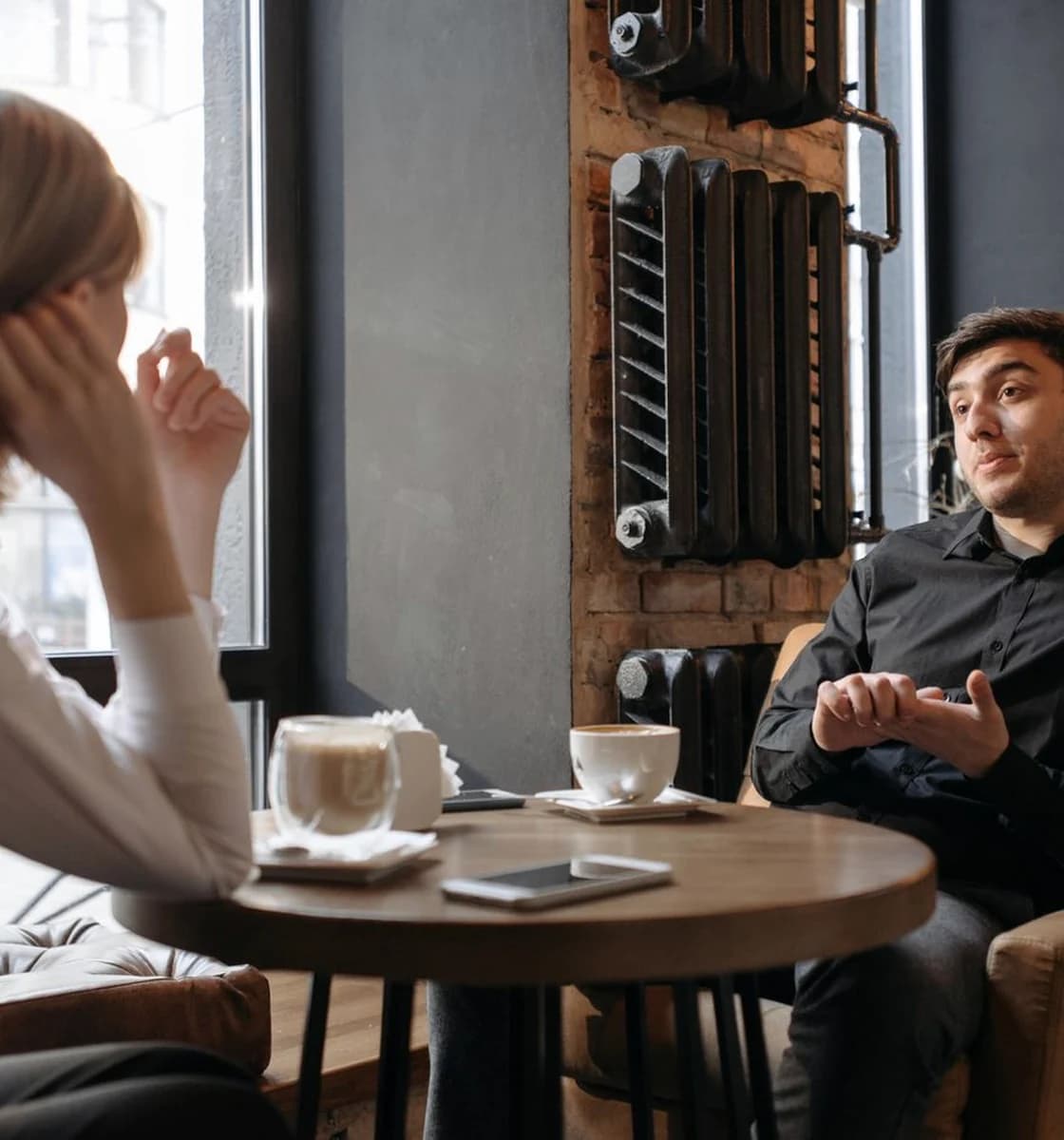 Two adults in a relaxed conversation at a warm café