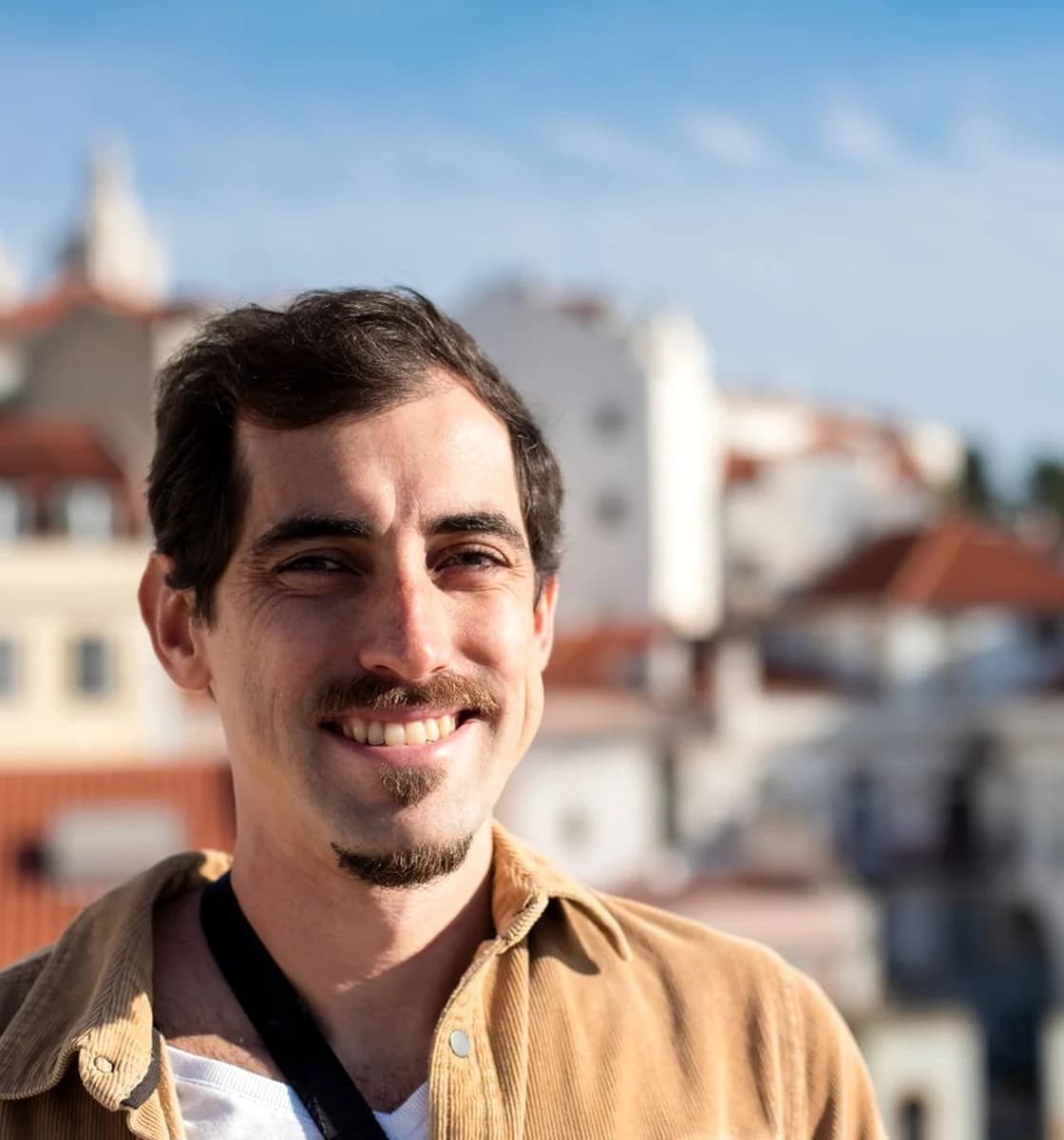 Adult man smiling naturally above a warm European cityscape