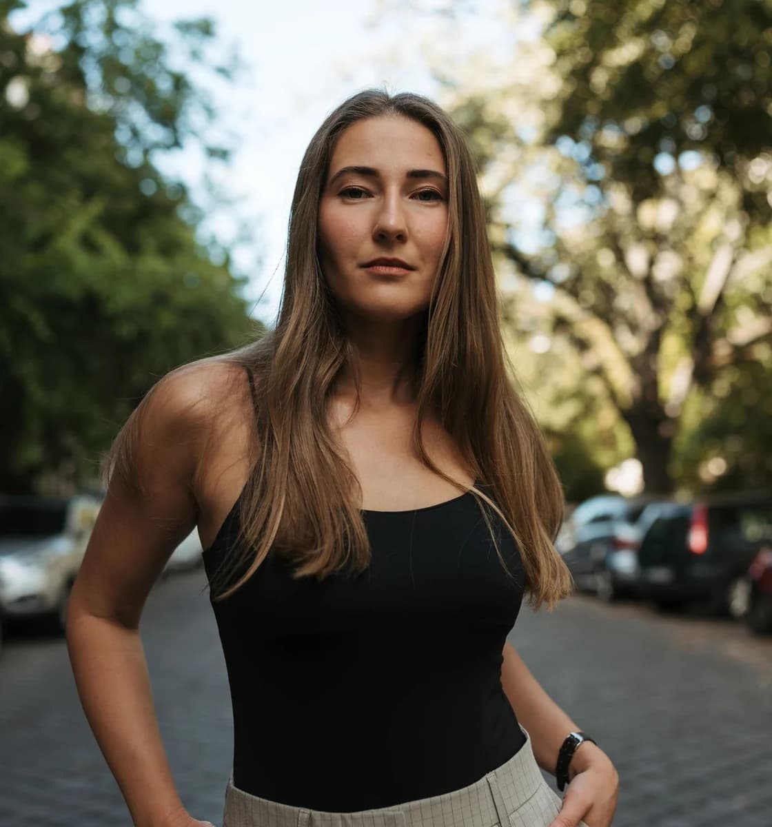 Adult woman standing on a quiet, leafy European street